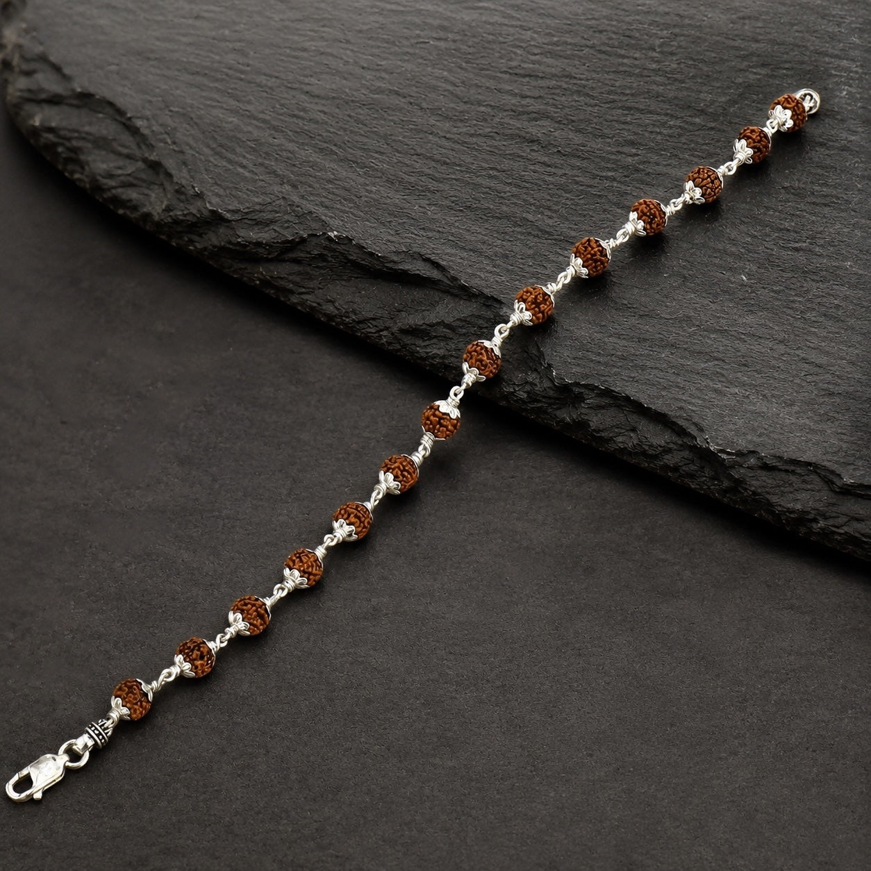 Close-up of 6–7 mm Rudraksha beads framed with floral silver caps